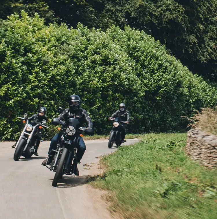 three motorcyclists coming round a left hand bend on a countryside road