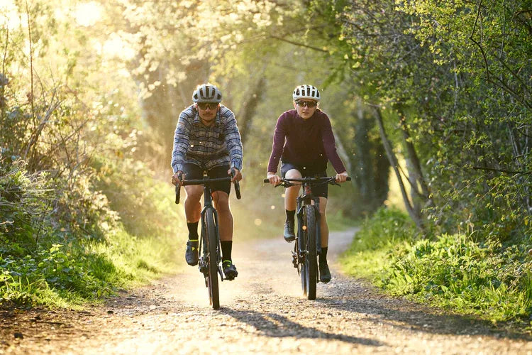 two cyclists riding down a gravel road